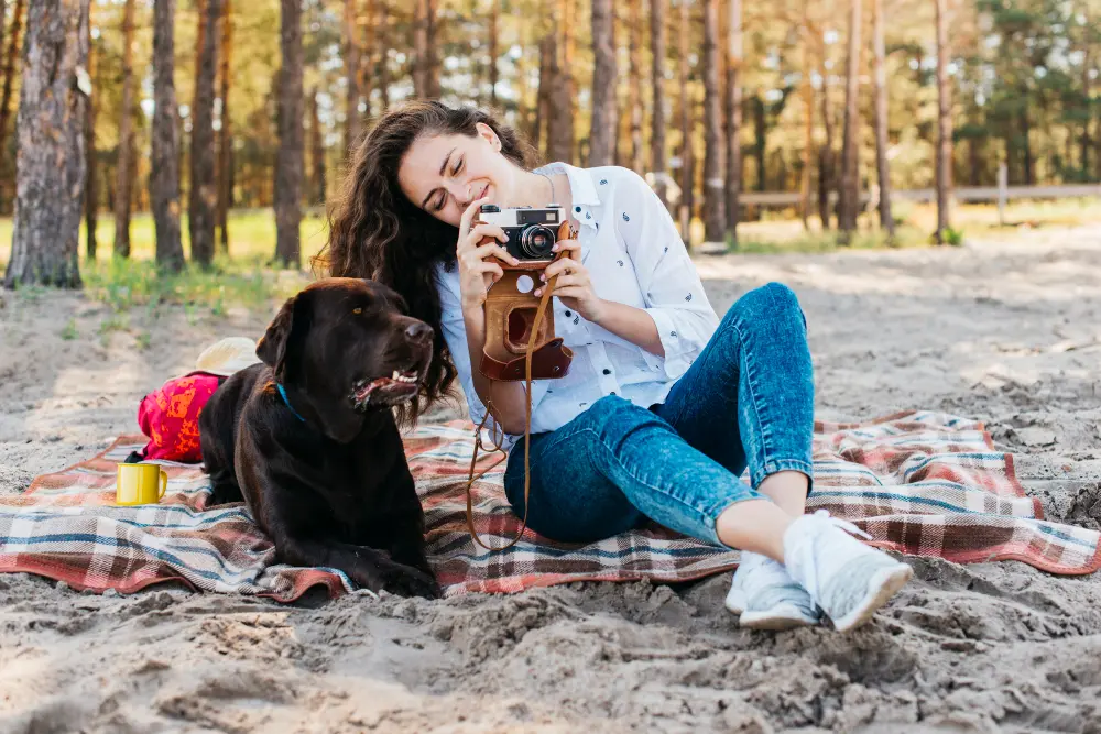 une femme souriante sur la plage avec son chien