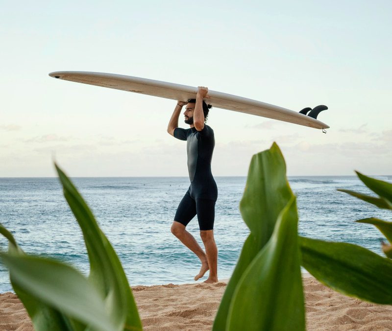 un hombre llevando su tabla de surf